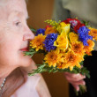 Elderly Woman Smelling Bouquet from Husband